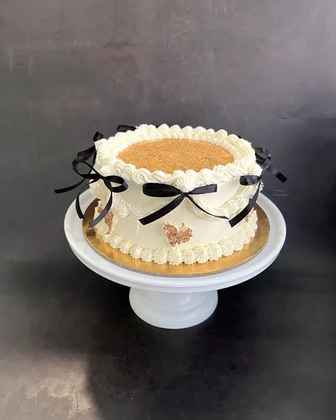 Tarta blanca con lazos negros en soporte