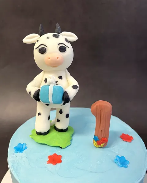 Vaquita de fondant sobre tarta azul